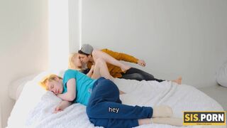 Guy satisfies blond stepsis behind her BF who is resting on bed