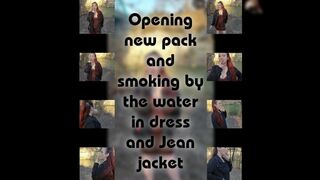 Opening a new pack and smoking by the water in a dress and jean jacket